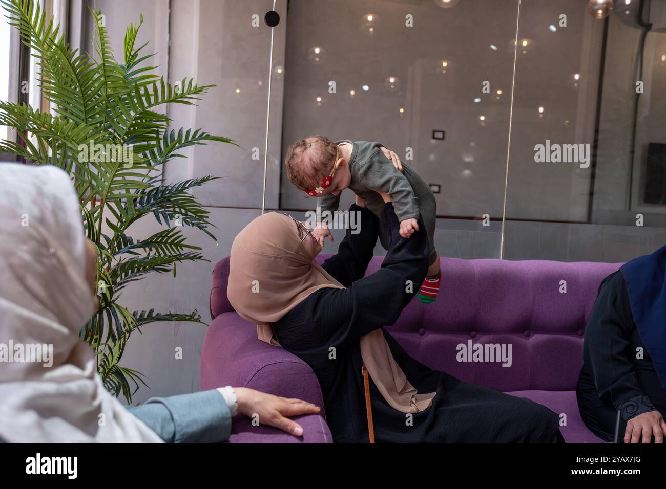 Zwei Frauen in Hijabs und ein Kind, das zusammen in einem Café sitzt, Gespräche teilt und Kaffee genießt. Die Szene zeigt ein warmes, familienfreundliches Atmosp Stockfoto