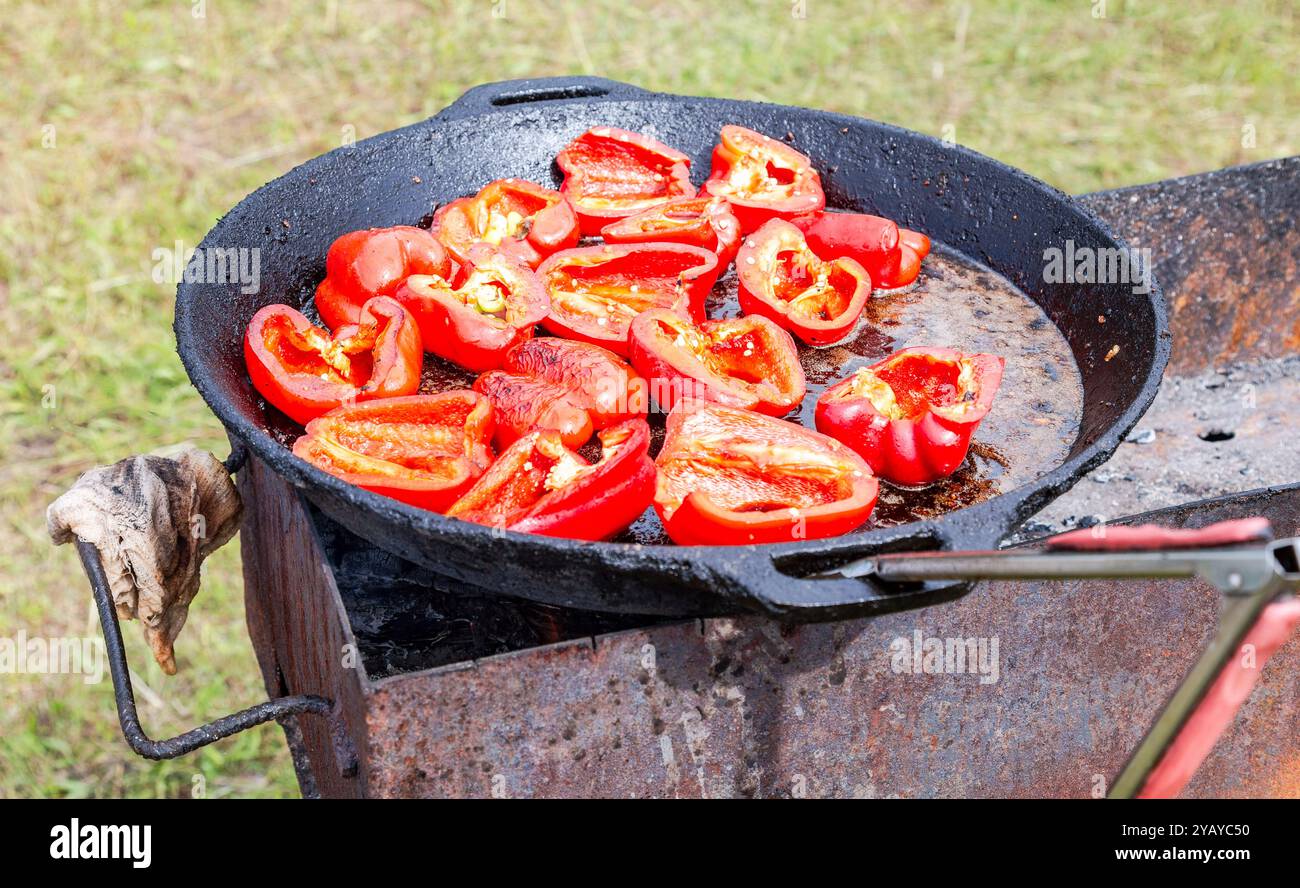 Gebratene Paprika in einer Pfanne über heißen Kohlen im Freien im Sommer Stockfoto
