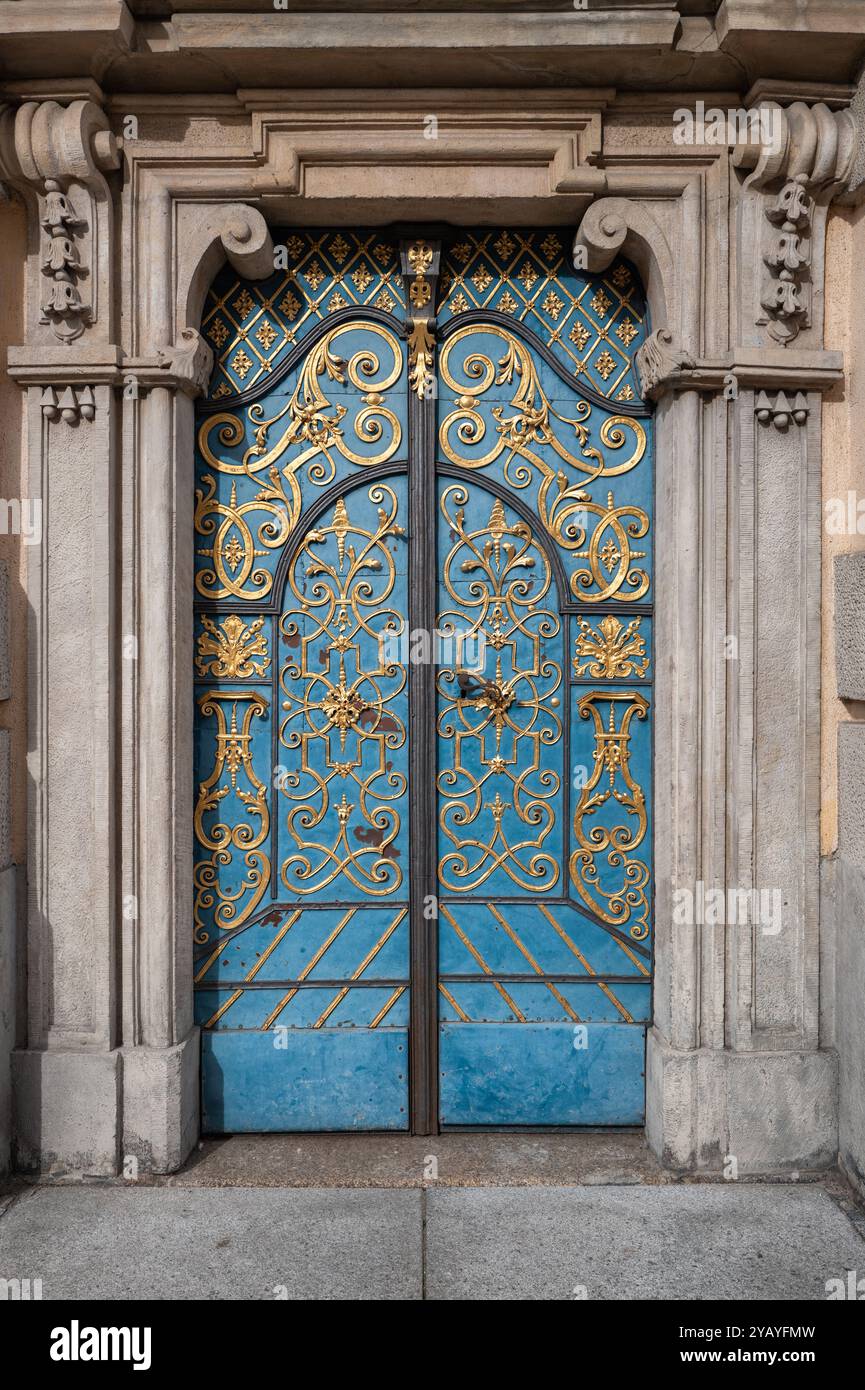 Ein wunderschön verziertes blaues Eisentor betont den Eingang eines historischen Gebäudes und zeigt raffinierte Handwerkskunst und architektonische Details im Th Stockfoto