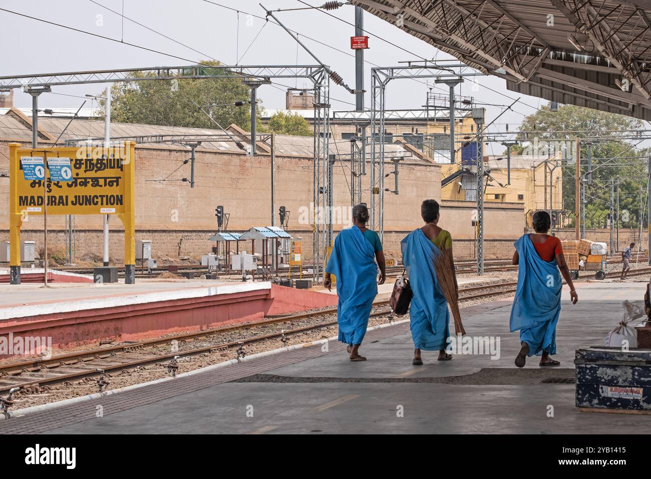 Drei Reisende spazieren am Hauptbahnhof Madurai, Tamil Nadu, auf einen Bahnsteig, der auf die Ankunft eines Zuges wartet Stockfoto