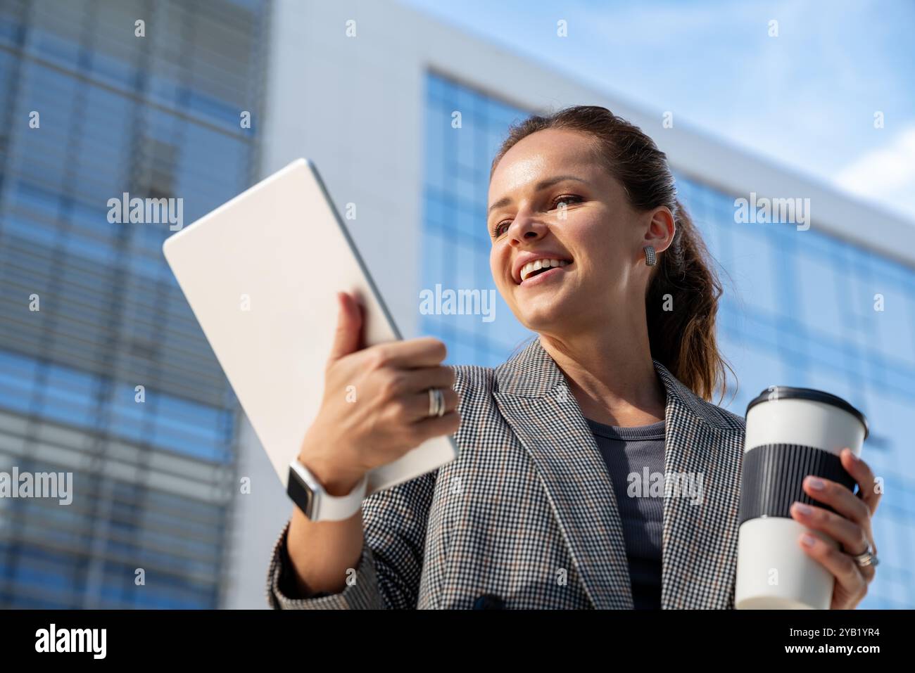 Geschäftsfrau, die ihr digitales Tablet vor dem Hintergrund eines Unternehmens oder Gebäudes verwendet. Cybersicherheit, E-Commerce, KI-Technologie, Elektronikindustrie. Stockfoto