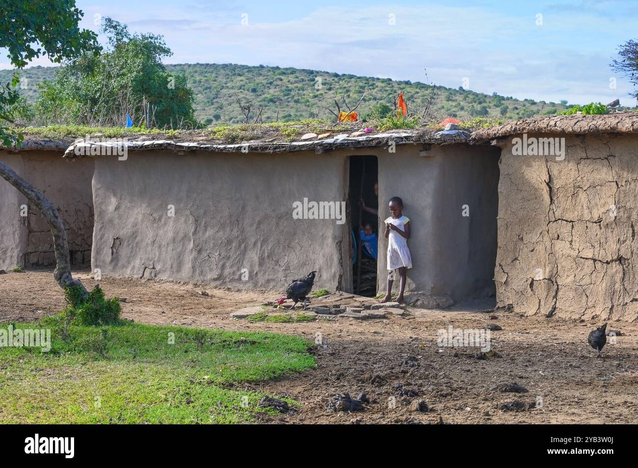 MAASAI MARA NATIONAL RESERVE, KENIA, AFRIKA - 11. NOVEMBER 2022: Maasai Girl steht vor einem traditionellen Haus in einem Maasai-Dorf in Kenia, Afrika Stockfoto