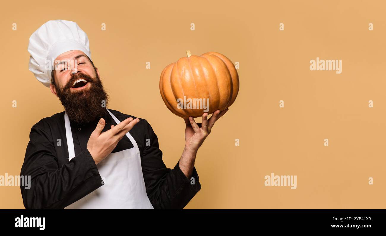 Bärtiger Mann in Küchenuniform mit Kürbis für Halloween. Thanksgiving-Tag kochen. Gesunde vegetarische Ernährung. Herbstrezepte. Koch-Mann in Kochmütze mit Stockfoto