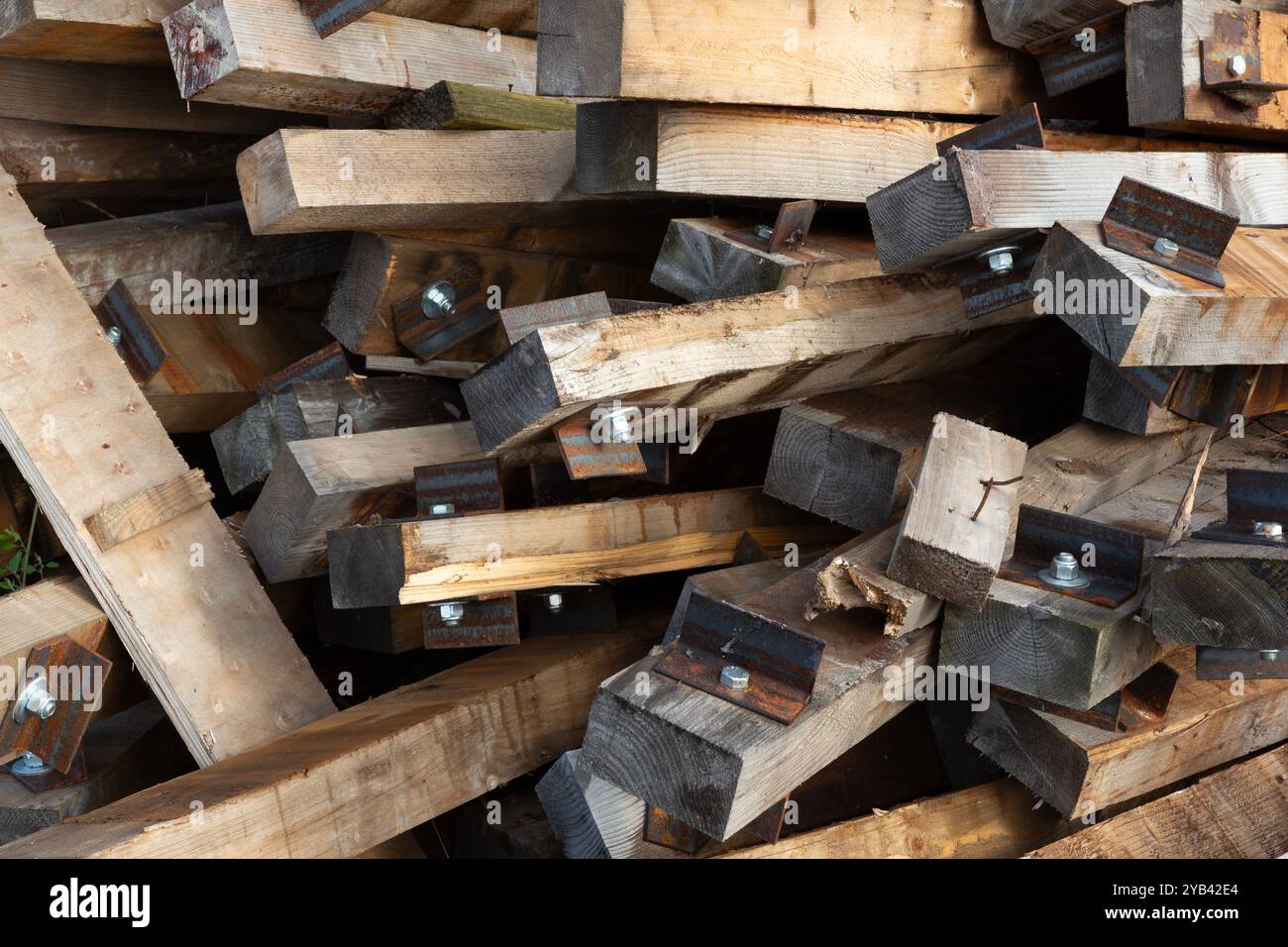 Nahaufnahme eines Stapels sortierter hölzerner Bahnschwellen mit Schrauben und Halterungen. Stockfoto