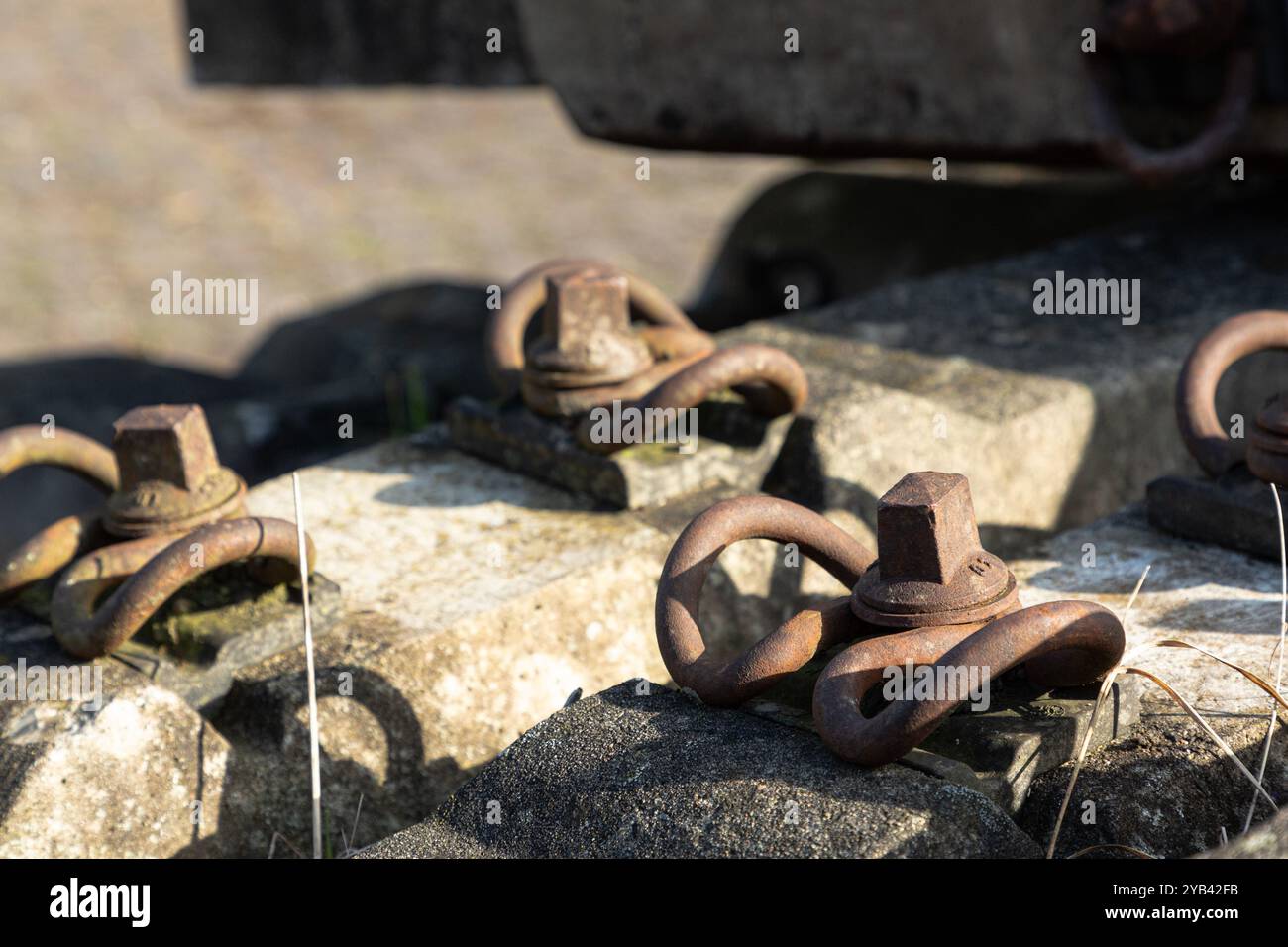 Rostige Schienenklemmen werden an alten, verwitterten Betonschwellen montiert. Stockfoto