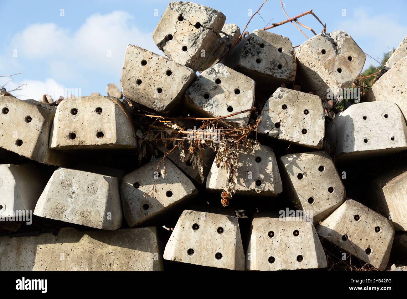 Nahaufnahme eines Haufens von verlassenen Betonschwellen mit getrockneten Ästen vor blauem Himmel. Stockfoto
