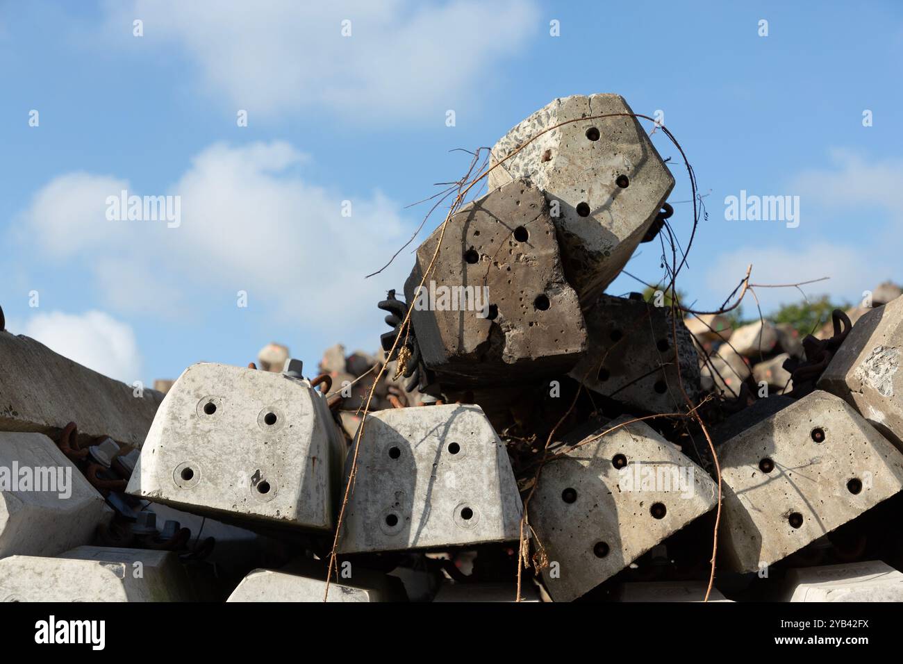 Nahaufnahme eines Haufens von verlassenen Betonschwellen mit getrockneten Ästen vor blauem Himmel. Stockfoto