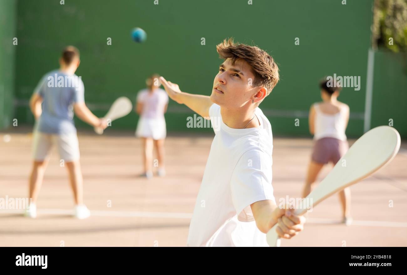 Junger Mann mit Holzpaleta spielt Pelota goma auf dem Freigelände Stockfoto