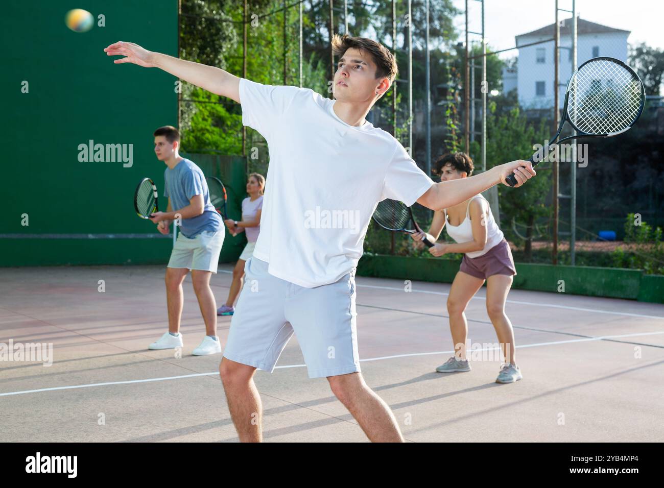 Sportlicher aktiver Mann während des Freundschaftsdoppel-Paarspiels. Zwei Männer, die gemeinsam im Freien Frontenis spielen Stockfoto