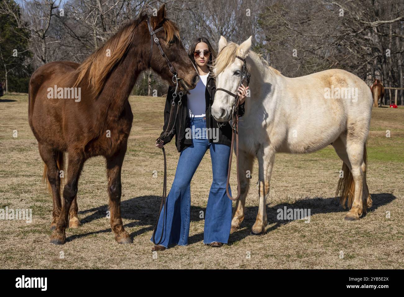 Ein wunderschönes braunes Cowgirl posiert mit ihrem Pferd, bevor es auf dem Land reitet Stockfoto