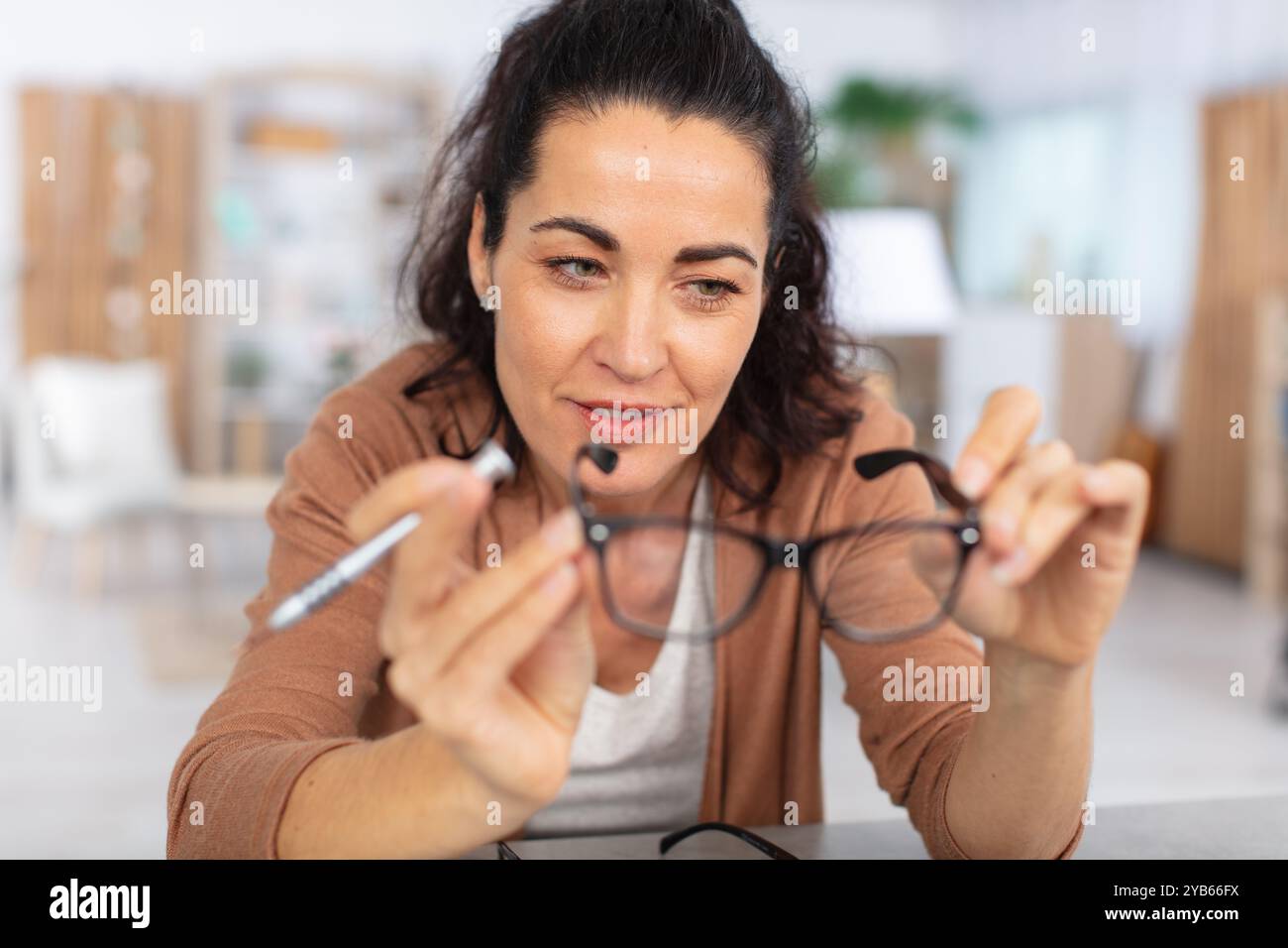 Schöne, selbstbewusste Frau, die eine Brille überprüft Stockfoto