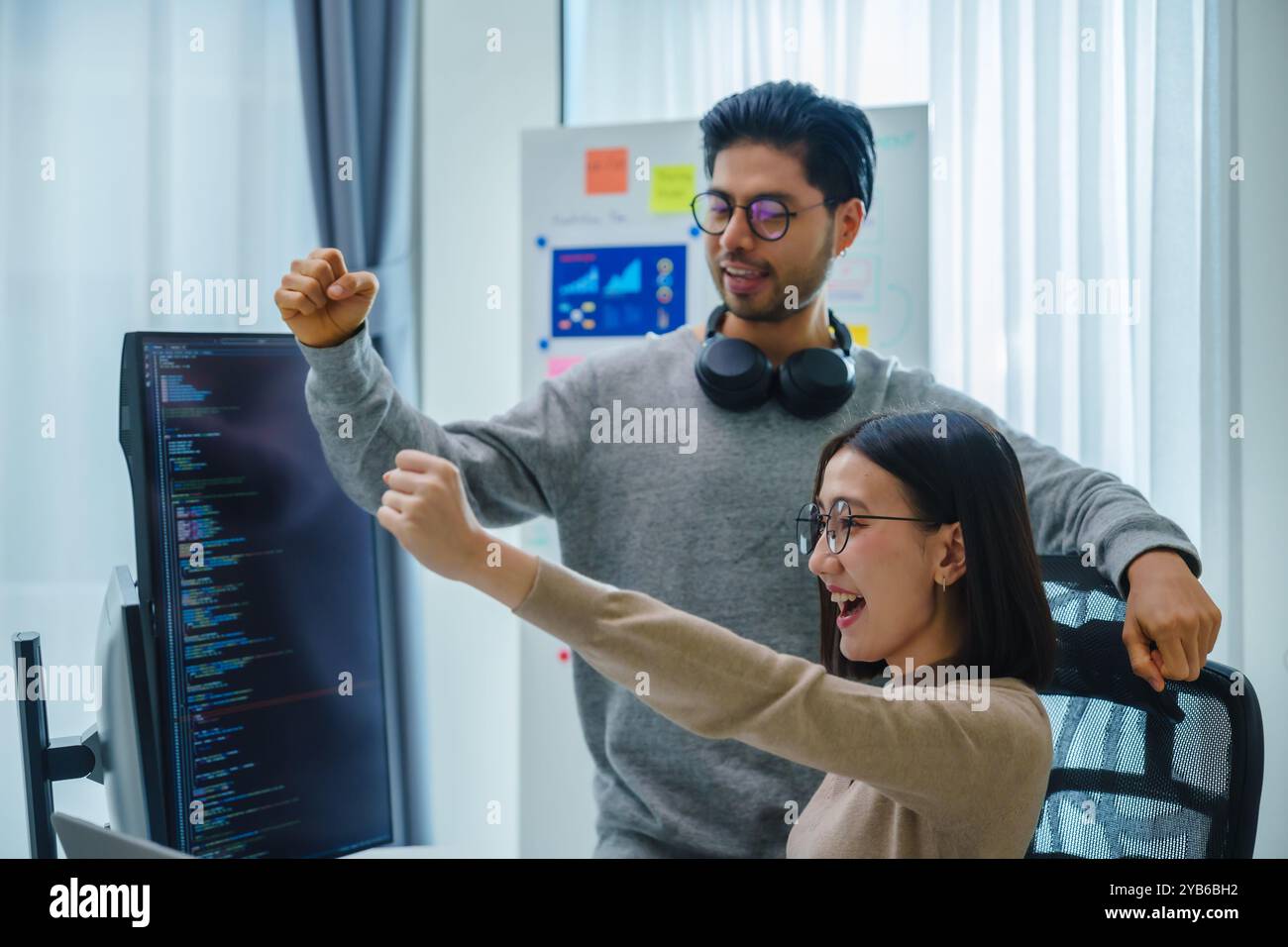 asiatische und indische Entwicklerteams klatschen Hand für Projekterfolg mit Software-Computer im Büro Stockfoto