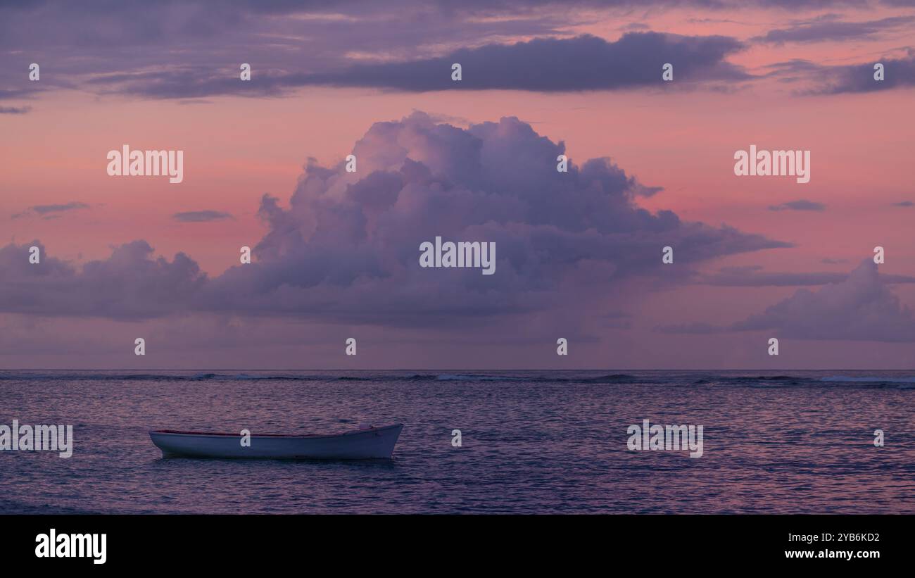 Fischerboot vor einem rosa Sonnenuntergang mit großer Wolke am Himmel Stockfoto