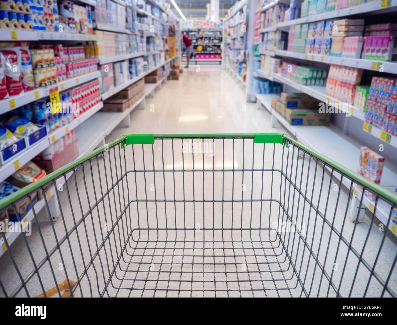 Einkaufswagen im Kaufhaus abstrakt verschwimmt von bunten Regalen, Einkaufswagen im Supermarkt. Leere rote Warenkorbansicht mit warmem Licht. Stockfoto