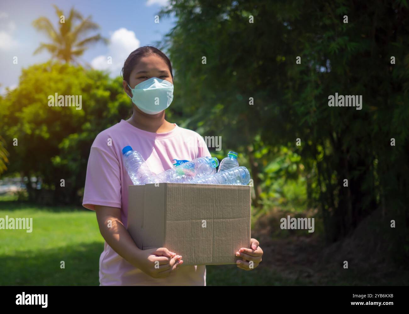 Recycle-Konzept, Frau sammelt Müll und hält einen Papierkorb mit Plastikflaschen im Freien, Kunststofffrei, Junk Food Plastikverpackung, R Stockfoto