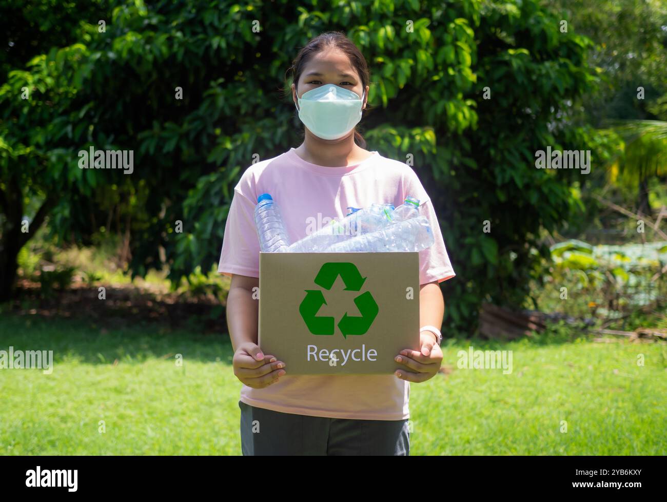 Reduzierung der Umweltverschmutzung und Recycling-Konzept, Frau sammelt Müll und hält einen Papierkorb mit Plastikflaschen im Freien, Plasti Stockfoto