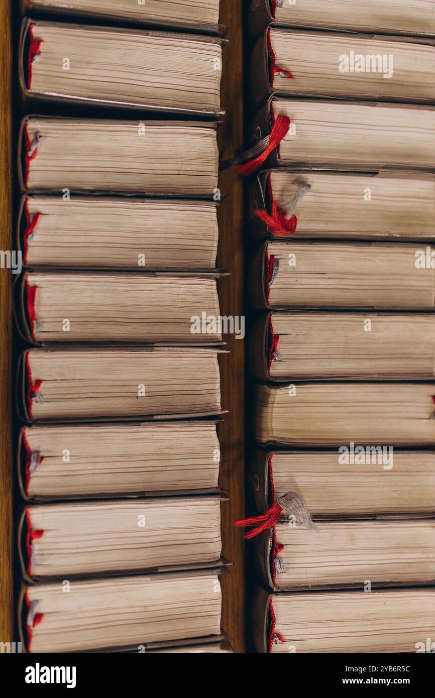 Blick von oben auf Reihen alter Bücher mit abgenutzten Seiten und roten Lesezeichen, ordentlich auf Holzregalen angeordnet. Hochwertige Fotos Stockfoto