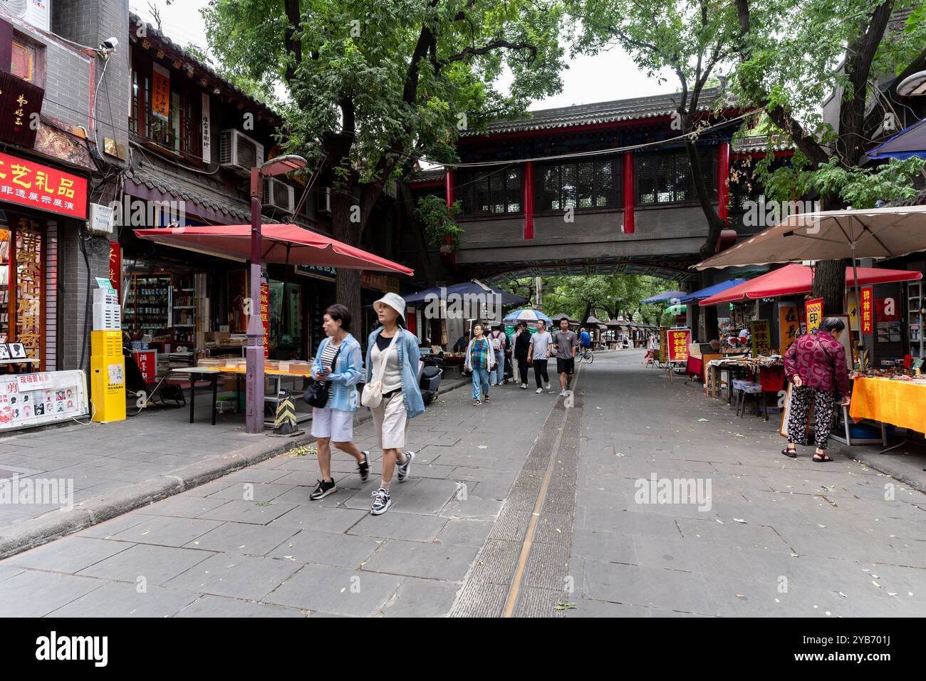 XI'an, China - 21. September 2024: Menschen gehen in der alten Kulturstraße Shuyuanmen in der Altstadt von Xi'an in der Nähe des Stadttors Yongningmen mit der Mauer Stockfoto