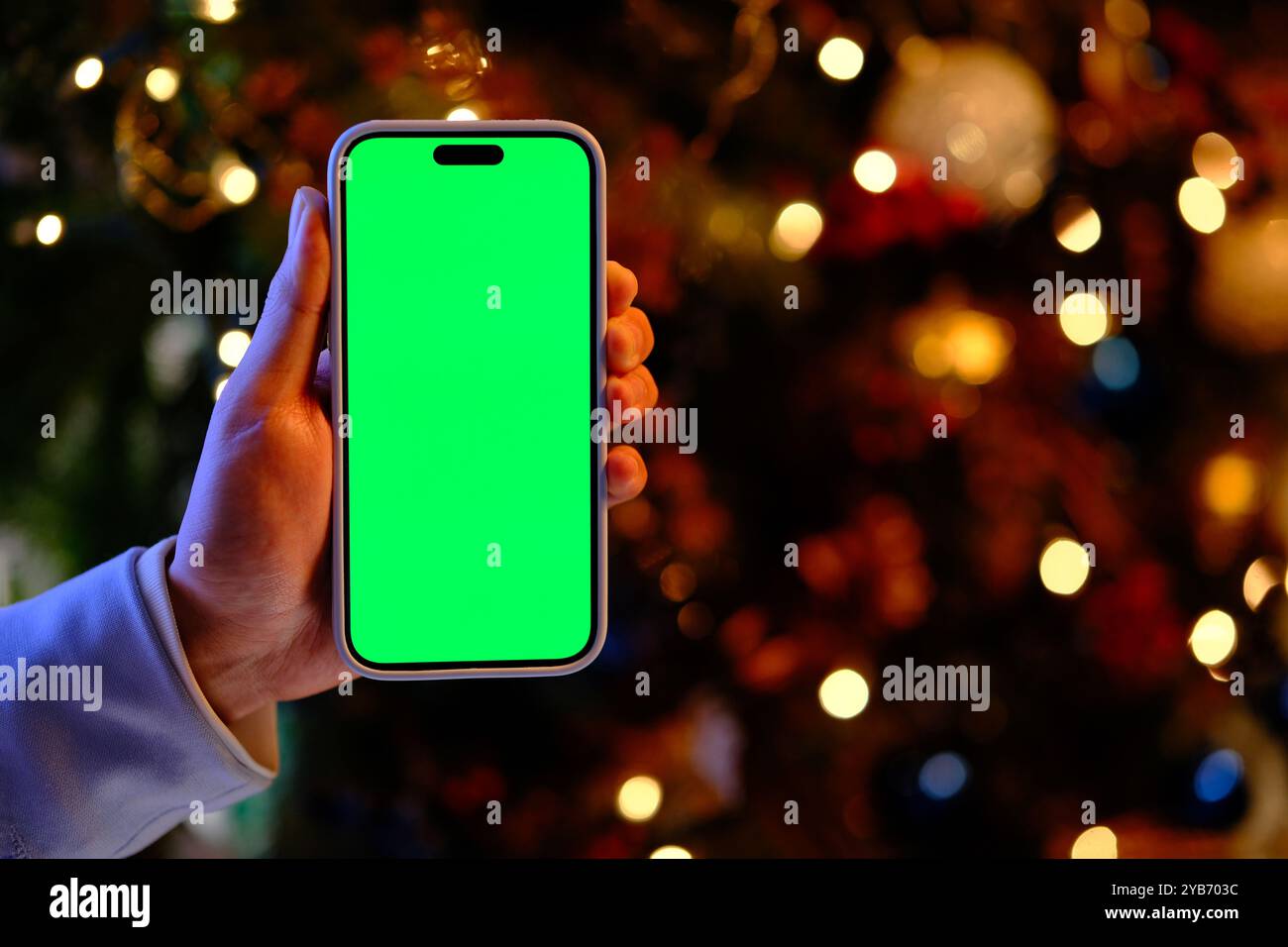 Hand zeigt das Green Screen Smartphone zu Weihnachten in der Nacht Stockfoto