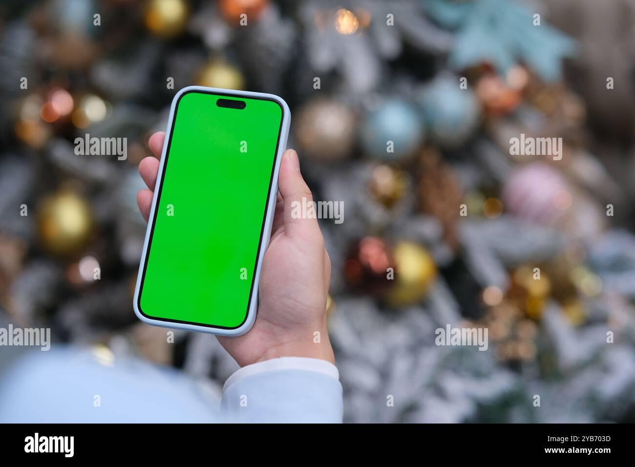 Hand mit dem Green Screen-Smartphone zu Weihnachten. Über die Schulter Stockfoto