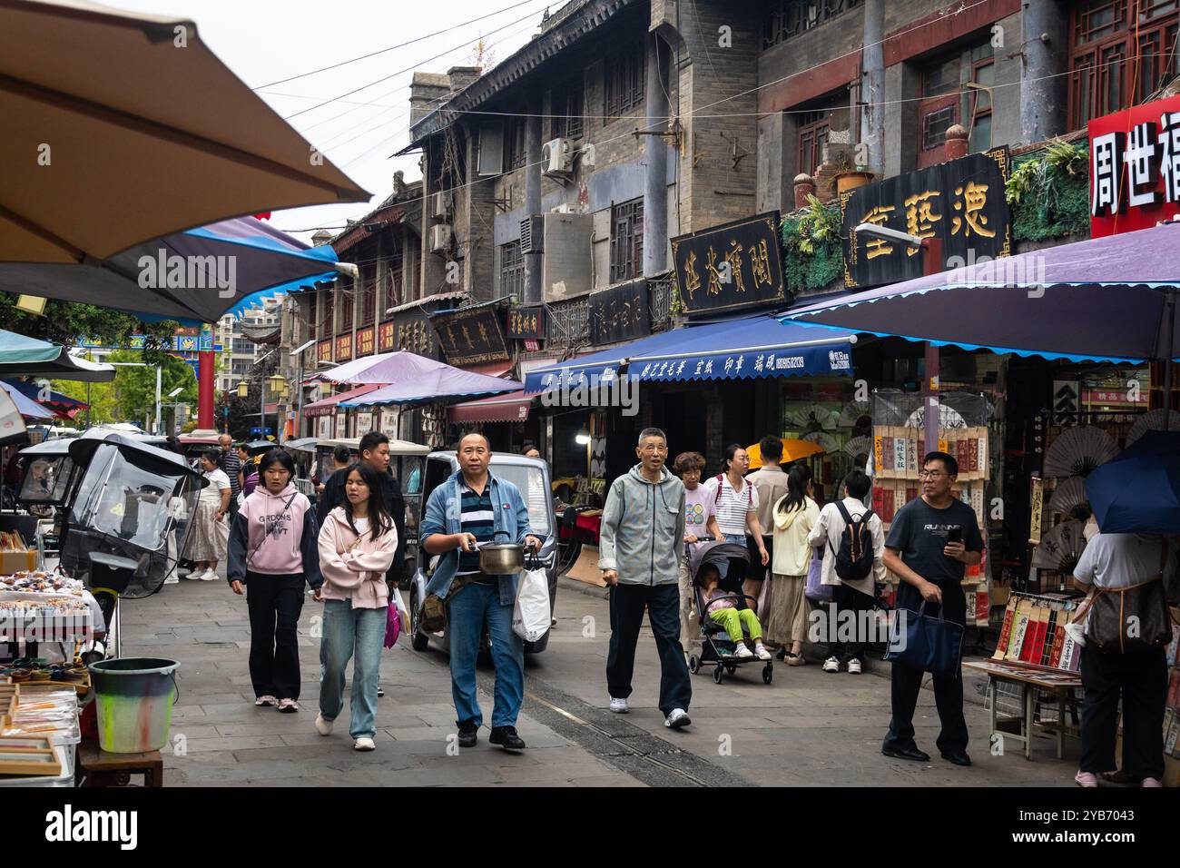 XI'an, China - 21. September 2024: Menschen gehen in der alten Kulturstraße Shuyuanmen in der Altstadt von Xi'an in der Nähe des Stadttors Yongningmen mit der Mauer Stockfoto