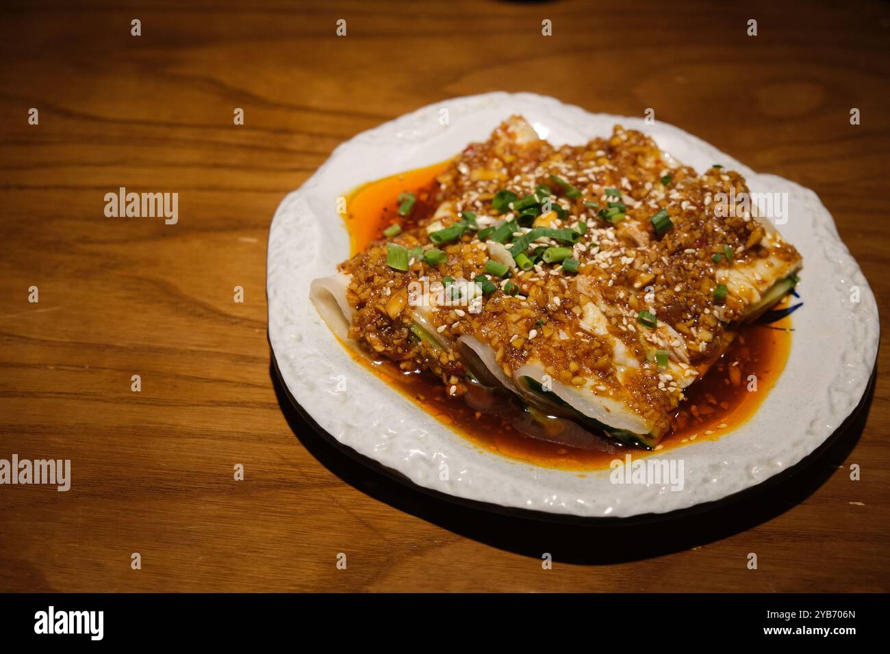 Teller mit Schweineschnitzel mit Knoblauchsoße auf Holztisch. Chinesische Sichuan-Küche Stockfoto