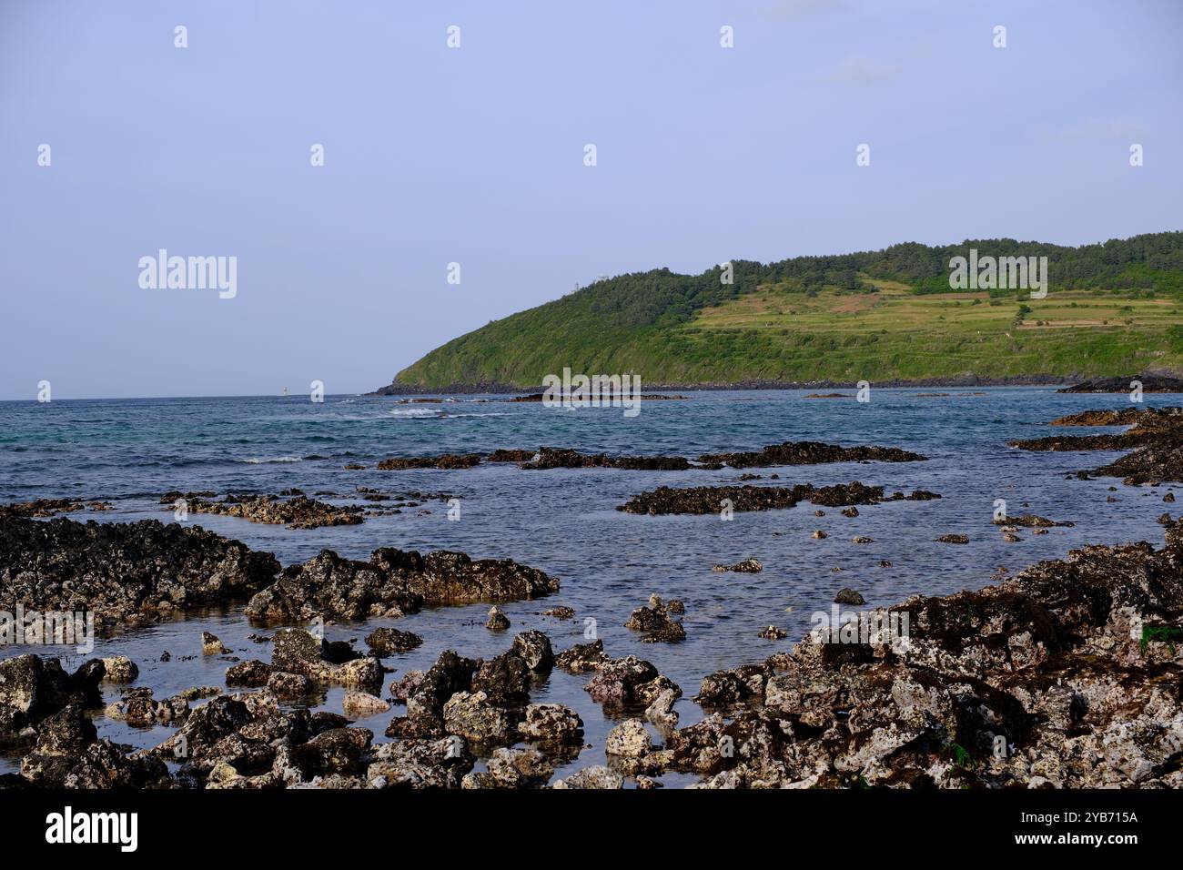 Landschaft mit Basaltfelsen, Meer und Seoubong-Gipfel am Hamdeok-Strand auf der Insel Jeju, Südkorea Stockfoto