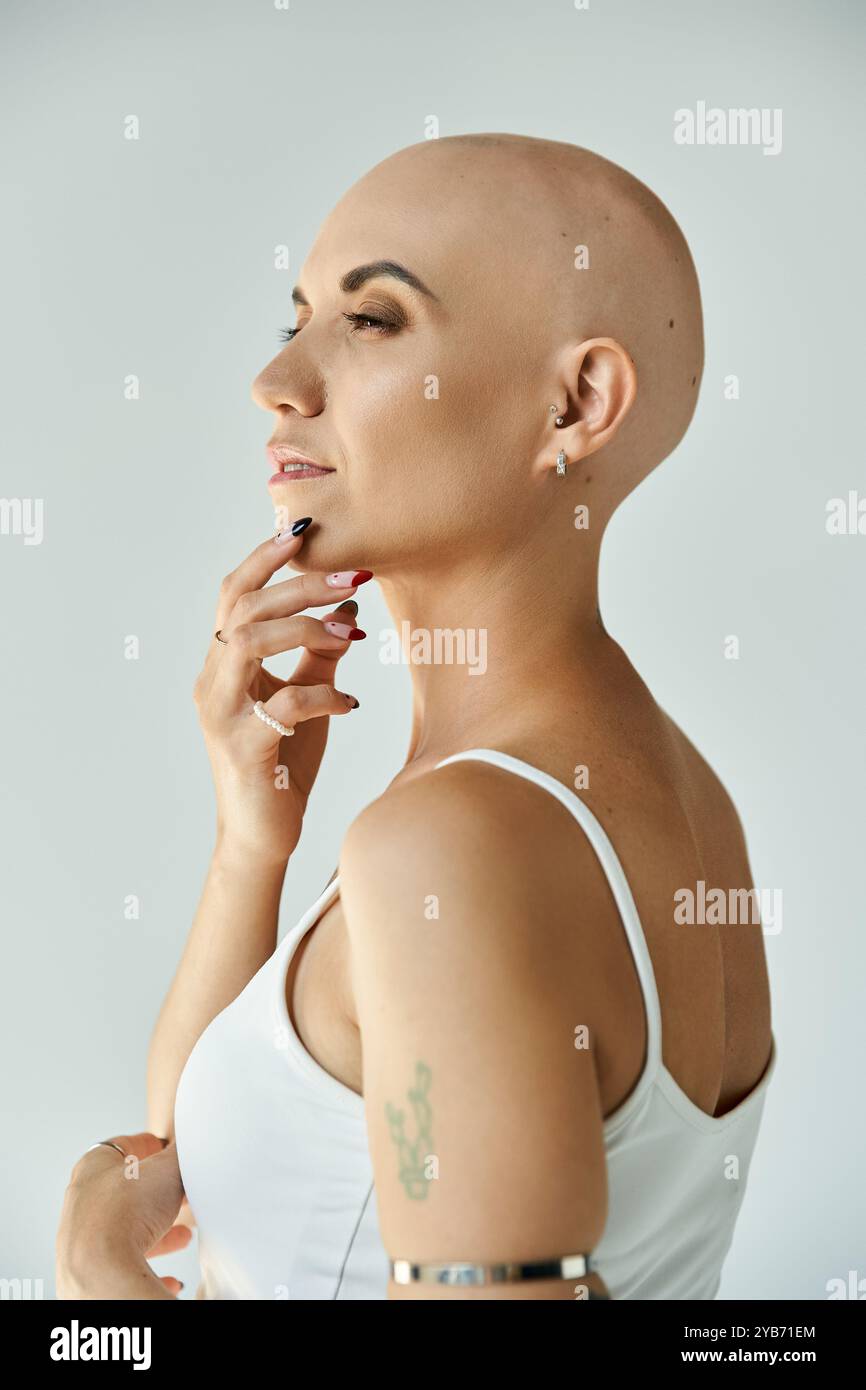 Eine junge kahlköpfige Frau mit Alopezie schlägt eine nachdenkliche Pose und strahlt Selbstvertrauen und Schönheit aus. Stockfoto