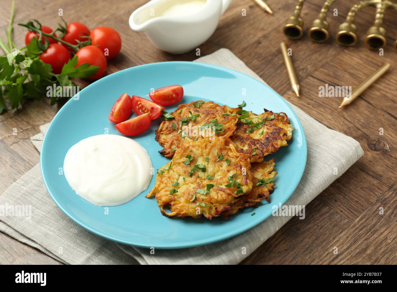 Leckere Kartoffelpfannkuchen, Menora und Kerzen auf Holztisch, Nahaufnahme. Hanukkah festliches Essen Stockfoto