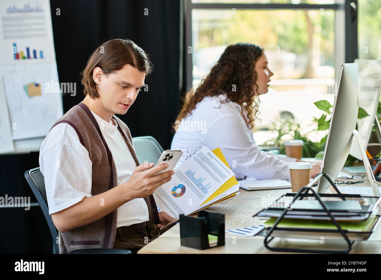 Eine junge Frau und ihr männlicher Freund konzentrieren sich auf ihre Aufgaben in einer stilvollen Büroumgebung. Stockfoto