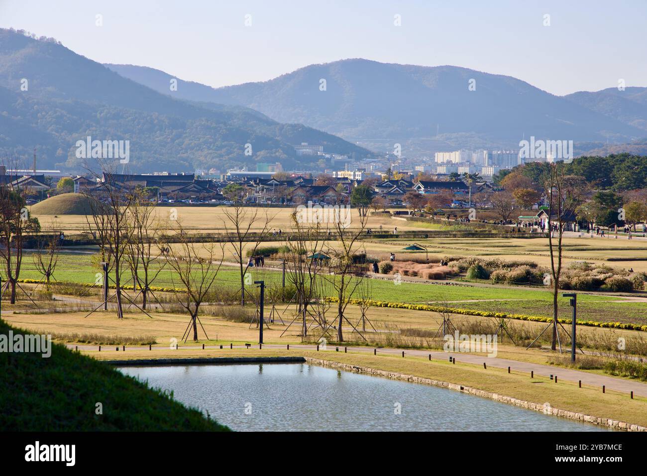 Gyeongju City, Südkorea - 11. November 2023: Panoramablick auf den Cheomseongdae Park mit üppigen grünen Feldern, von Bäumen gesäumten Wegen und weit entfernten Moun Stockfoto