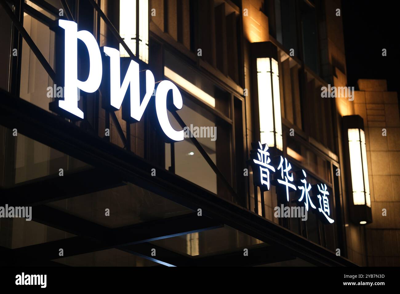 PwC (PricewaterhouseCoopers International Limited) Firmenlogoschild bei Nacht Stockfoto