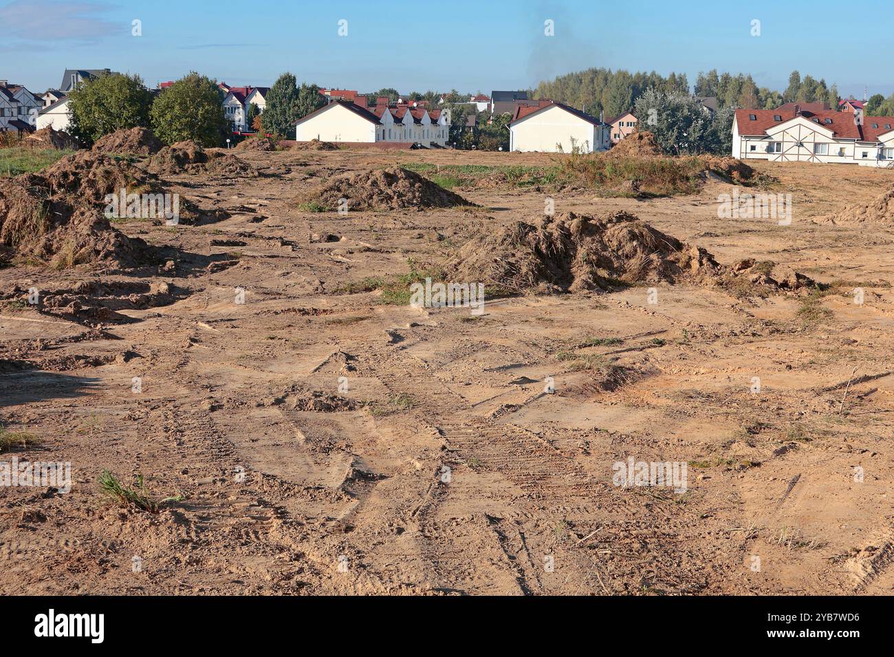 Bodenbelag für den Bau neuer Wohngegenstände. Grundstückshaufen auf der Baustelle vor dem Hintergrund von gebauten Häusern. Gebäude und Stockfoto