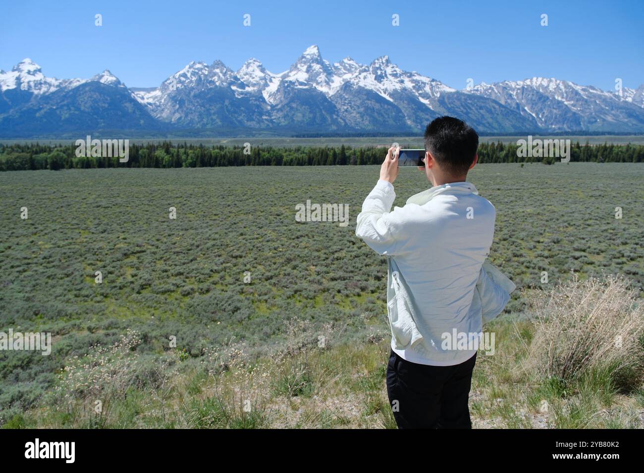 Mann in der mobilen Fotografie in Grand Teton, Berg der Teton Range im Grand Teton National Park. Touristen fotografieren mit dem Smartphone Stockfoto
