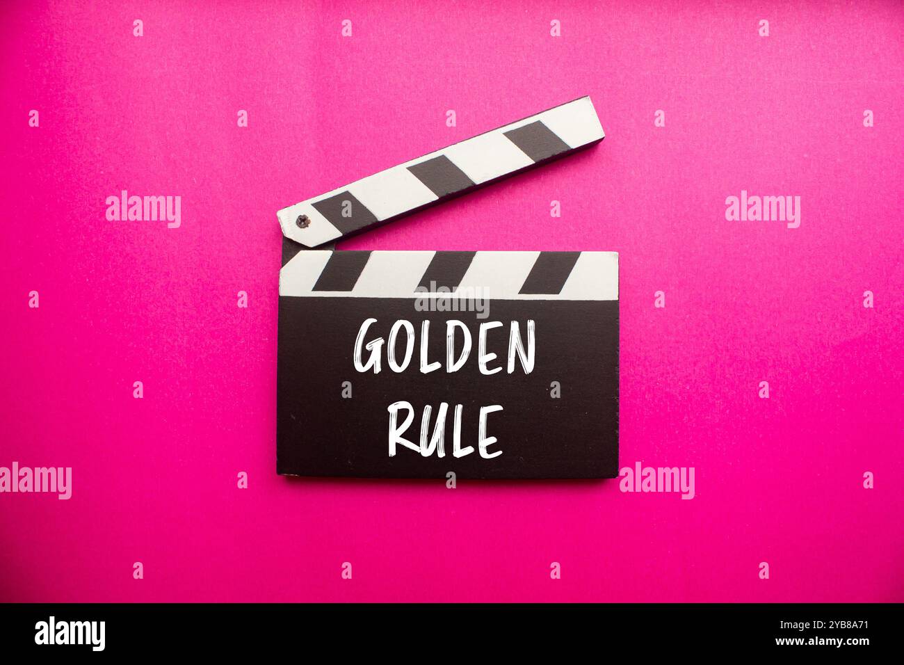 Goldene Regelnachricht auf Klapptafel mit rosa Hintergrund. Konzeptionelles goldenes Regelsymbol. Kopierbereich. Stockfoto
