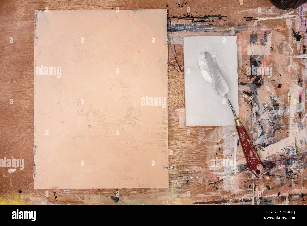 Draufsicht eines Künstlerdekstopps mit leerer texturierter Leinwand, Palettenmesser, Acrylfarbe auf einem unordentlichen rustikalen Holztisch. Kunststudio, Maler und cr Stockfoto
