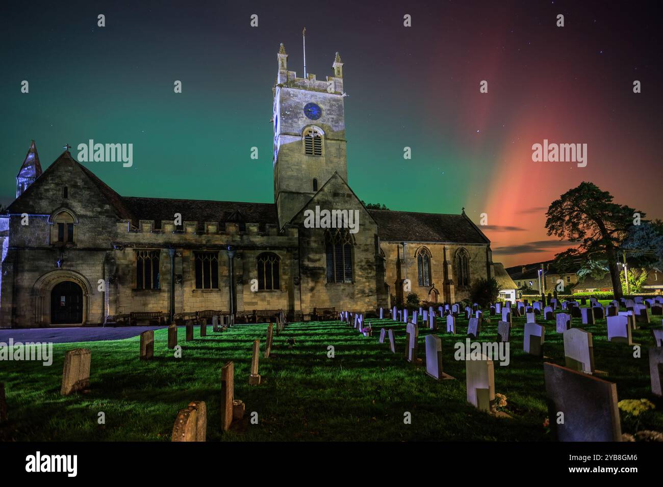 Die leuchtend roten und grünen Nordlichter bilden einen farbenfrohen Hintergrund für die Kirche St. Michaels in Bischofs Cleeve, Cheltenham. Stockfoto Die leuchtend roten und grünen Nordlichter bilden einen farbenfrohen Hintergrund für die Kirche St. Michaels in Bischofs Cleeve, Cheltenham. Stockfoto