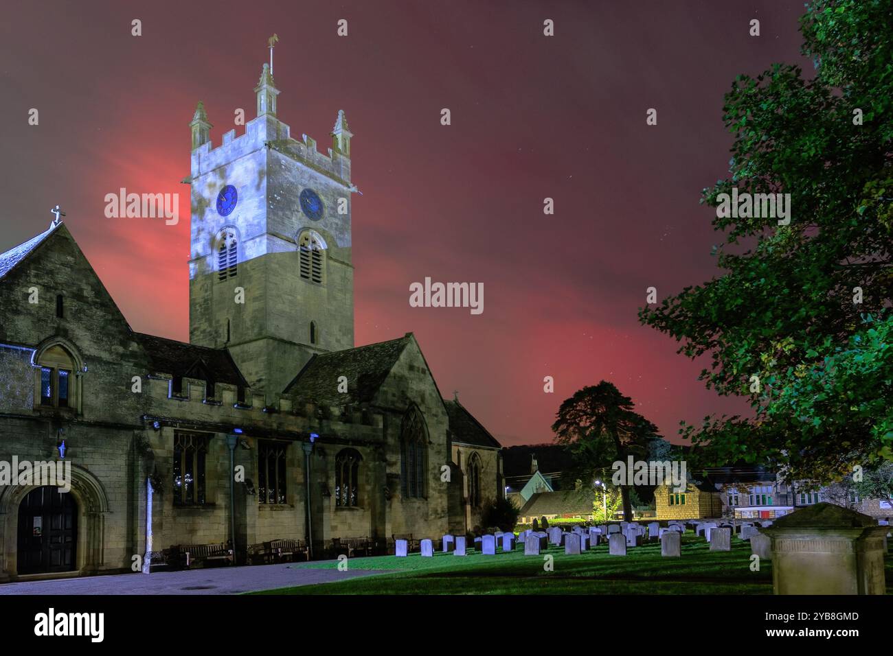 Die leuchtend roten und grünen Nordlichter bilden einen farbenfrohen Hintergrund für die Kirche St. Michaels in Bischofs Cleeve, Cheltenham. Stockfoto Die leuchtend roten und grünen Nordlichter bilden einen farbenfrohen Hintergrund für die Kirche St. Michaels in Bischofs Cleeve, Cheltenham. Stockfoto