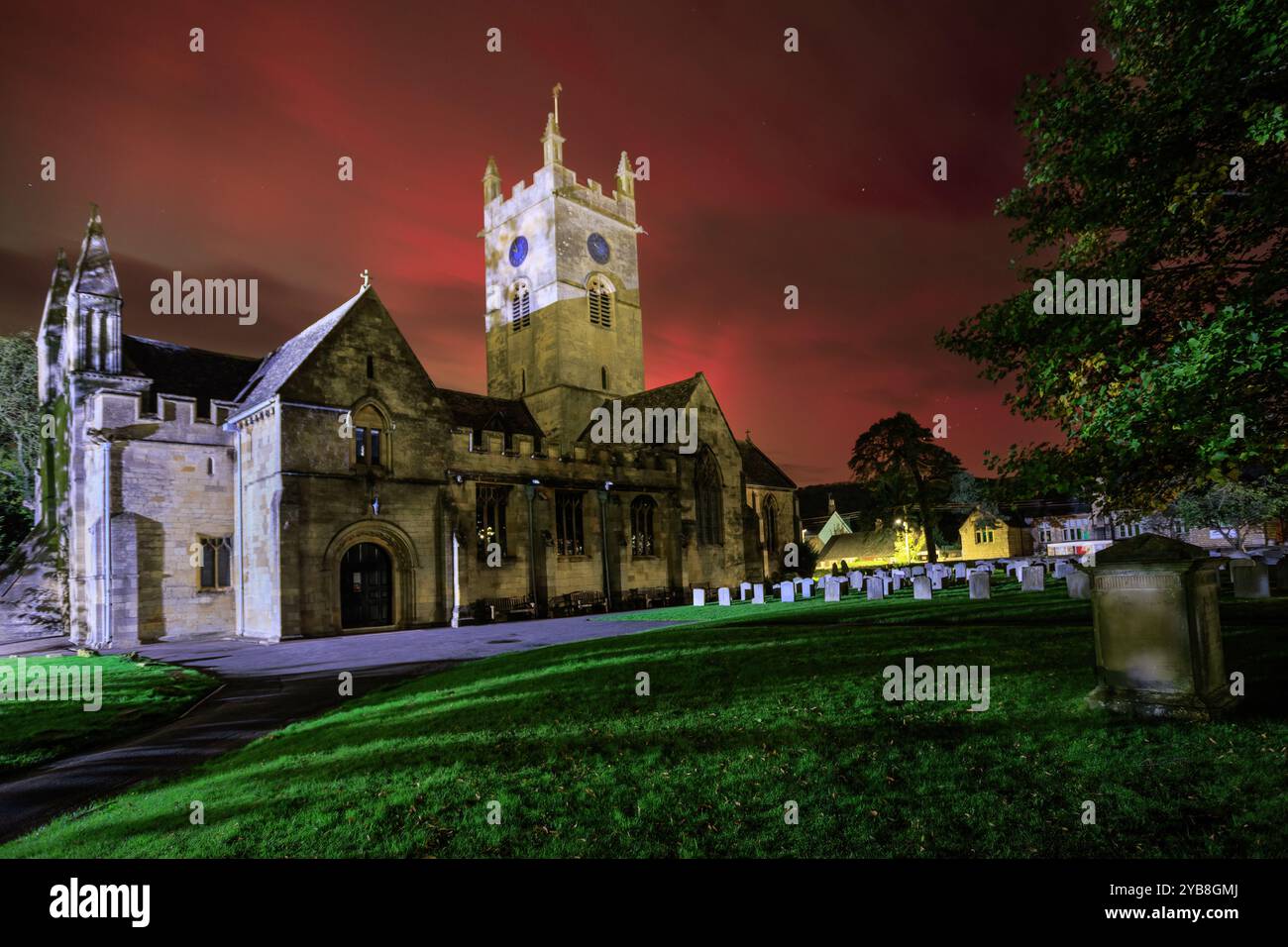 Die leuchtend roten und grünen Nordlichter bilden einen farbenfrohen Hintergrund für die Kirche St. Michaels in Bischofs Cleeve, Cheltenham. Stockfoto Die leuchtend roten und grünen Nordlichter bilden einen farbenfrohen Hintergrund für die Kirche St. Michaels in Bischofs Cleeve, Cheltenham. Stockfoto