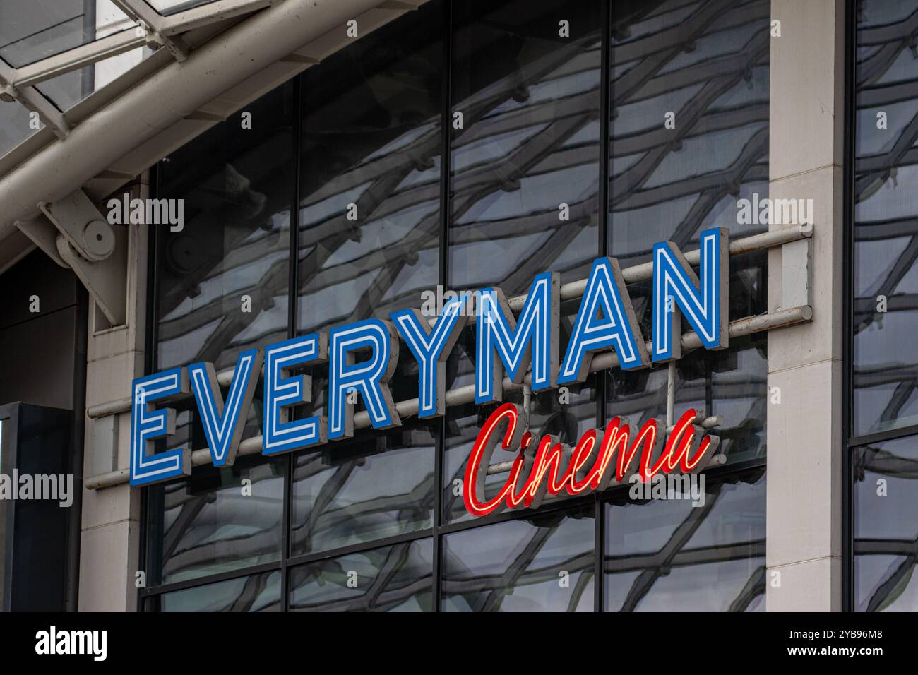 Eine Nahaufnahme eines blau-weißen Everyman Cinema Schildes mit einem roten Neon Cinema darunter, montiert auf einem modernen Gebäude mit großen Glaspaneelen. Stockfoto