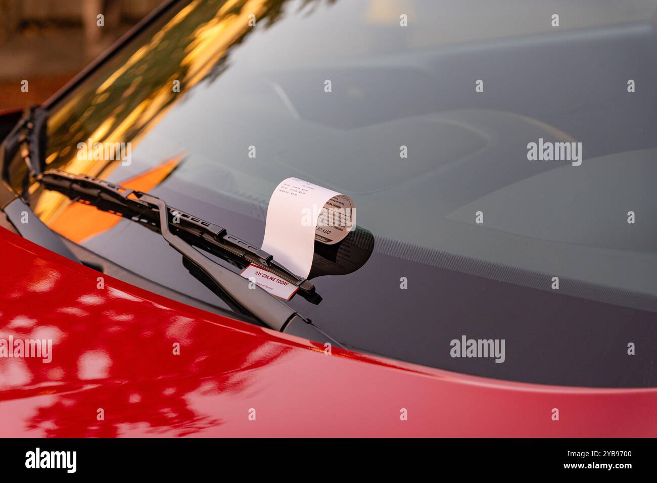 Parkschein auf der Windschutzscheibe des geparkten roten Autos. Stockfoto