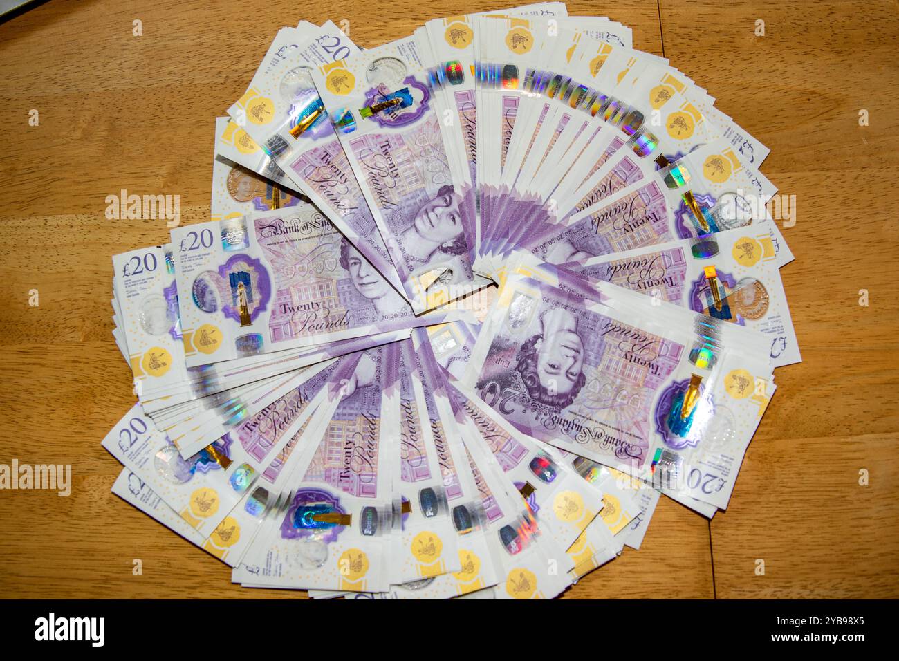 Ein kreisförmiges Arrangement britischer 20-Pfund-Noten auf einer hölzernen Oberfläche. Die Noten sind aufgefächert und zeigen ihre violette Farbe und ihre Komplexität Stockfoto