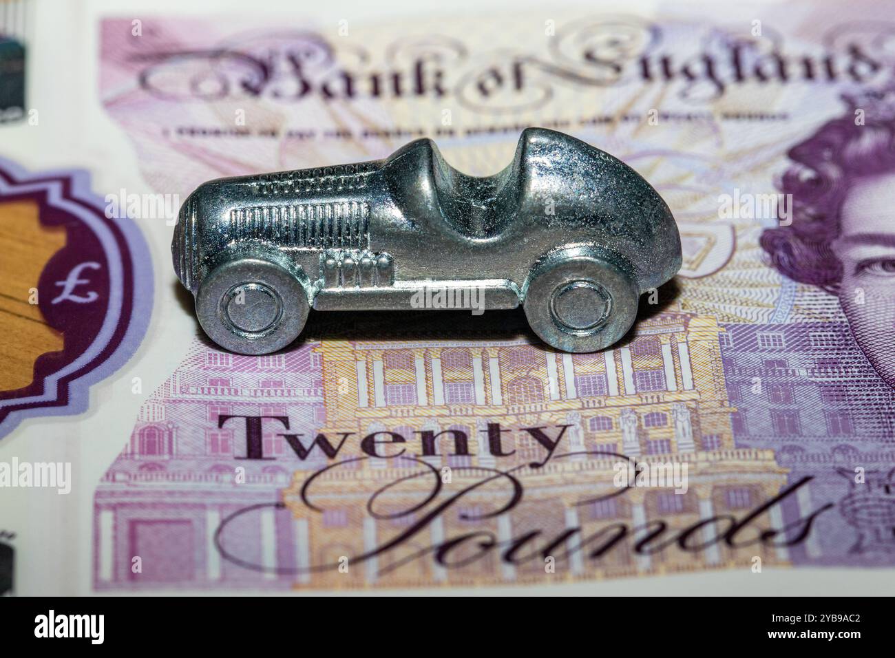 Eine silberne Monopolmarke sitzt auf einer britischen Banknote, die teilweise das Wort Twenty verdeckt. Stockfoto