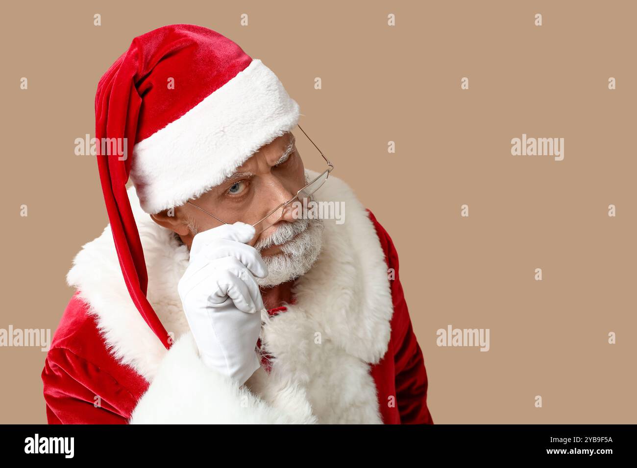 Verdächtiger Weihnachtsmann in Brille auf braunem Hintergrund Stockfoto