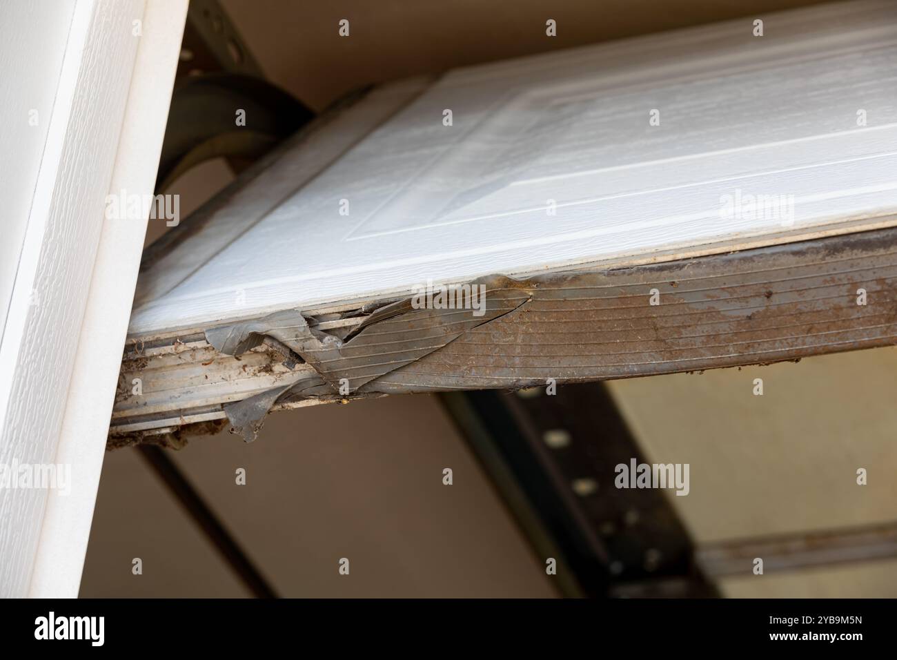 Wetterfeste Abisolierdichtung für Garagentor gerissen und gebrochen. Heimwetterschutz, Reparatur und Nagetierprävention. Stockfoto