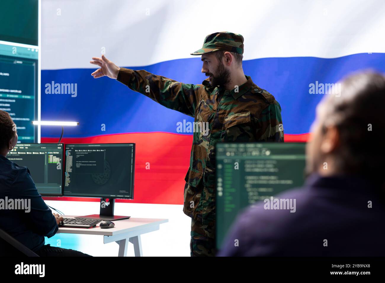 Russischer Armeeoffizier überwacht Cyberangriffe auf staatliche Netzwerke, verbreitet Fehlinformationen und Fake News in Europa während des Hybridkriegs. Militärangehörige arbeiten an Betrug und Hacking. Stockfoto