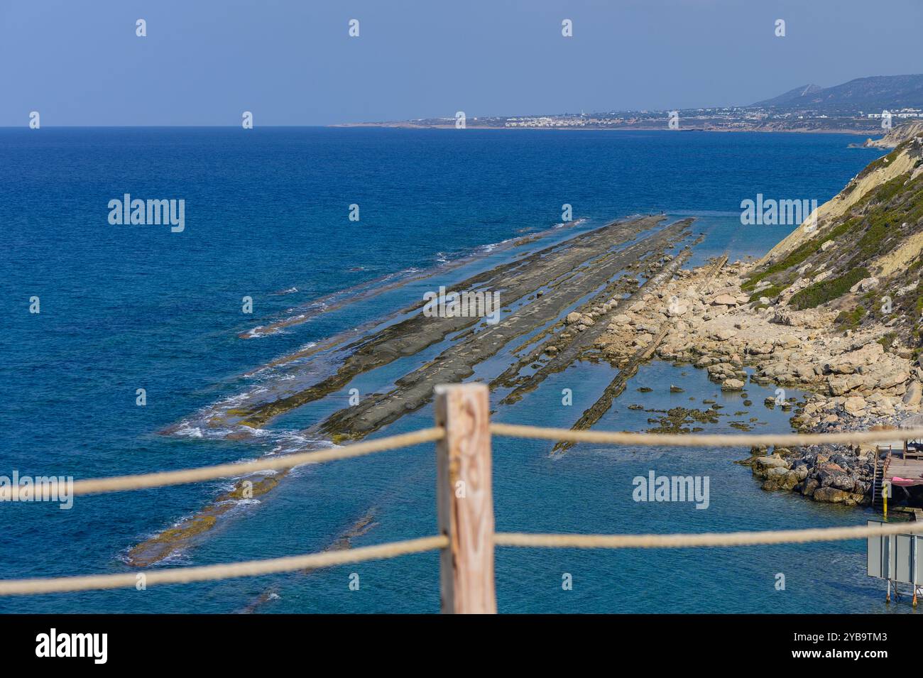 Eine atemberaubende Weite aus azurblauem Wasser trifft auf zerklüftete Felsformationen und schafft eine malerische Küstenlandschaft unter klarem Himmel. Die Ruhe des af Stockfoto