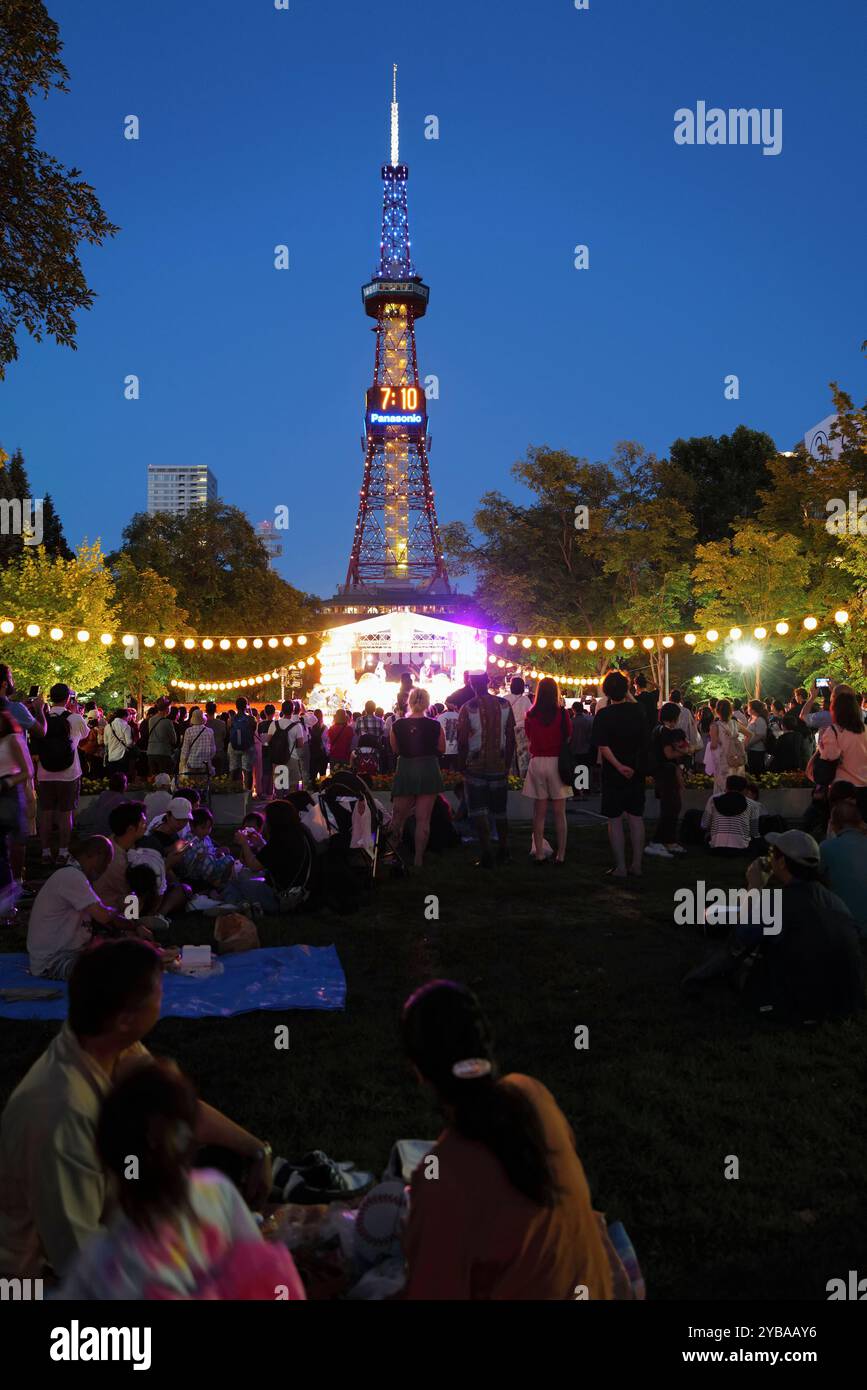 Der Blick in die Dämmerung auf das traditionelle Picknick-Treffen am Mountain Day Festival im Odori Park mit Sapporo Turm im Hintergrund. Sapporo.Hokkaido.Japan Stockfoto