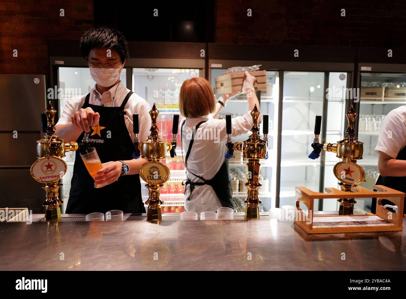 Arbeiter, die Bier für Besucher in der Star Hall der bezahlten Testhalle im Sapporo Biermuseum.Sapporo.Hokkaido.Japan gießen Stockfoto