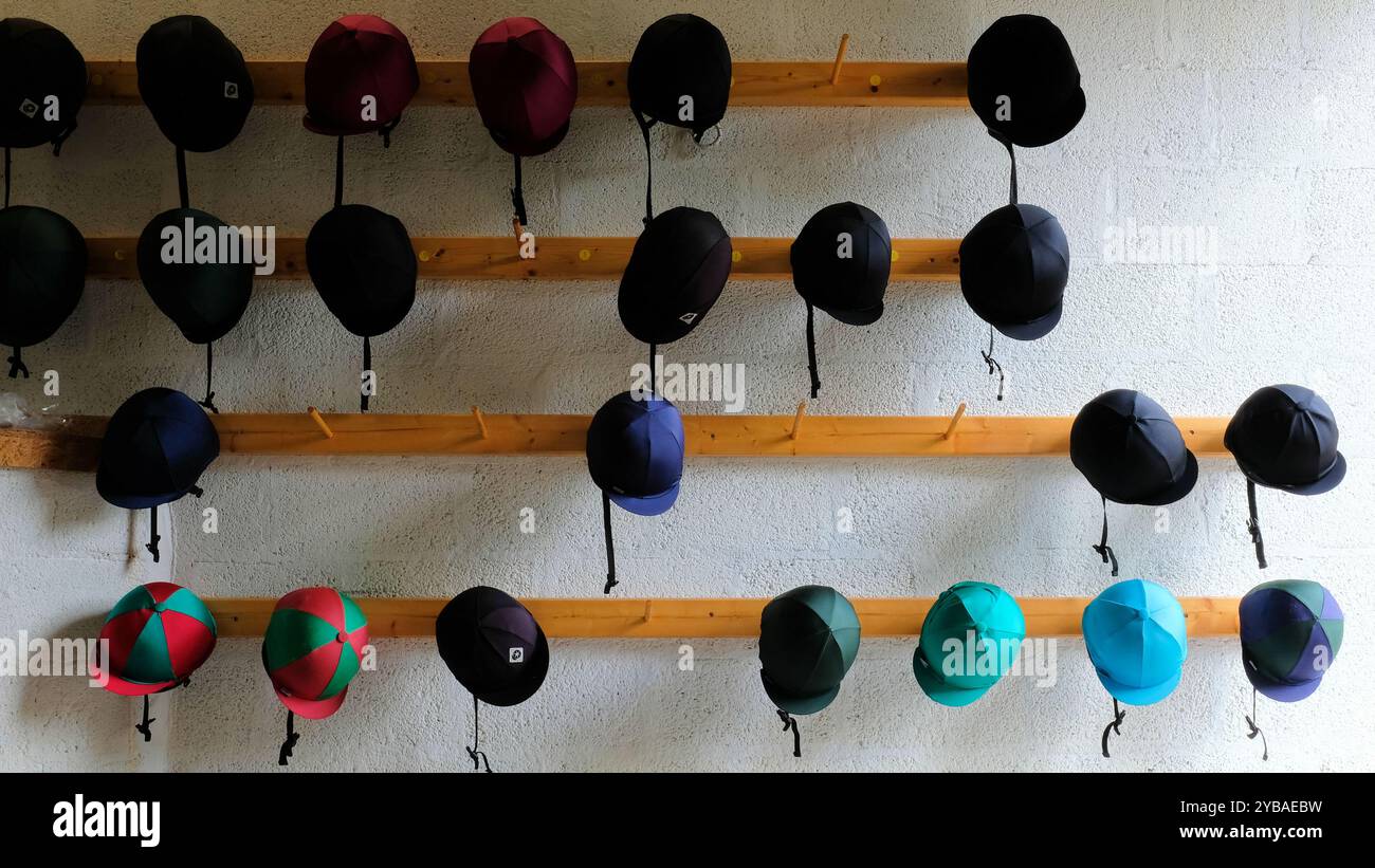 Reithelme hängen an der Wand; Schutzkopfbekleidung beim Reiten von Pferden; Reitschutzhelm; Verhütung von Kopfverletzungen. Stockfoto